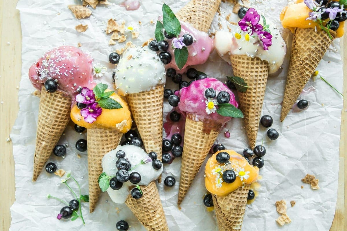 A spread of custard and sorbet cones dressed with berries and edible flowers for an event