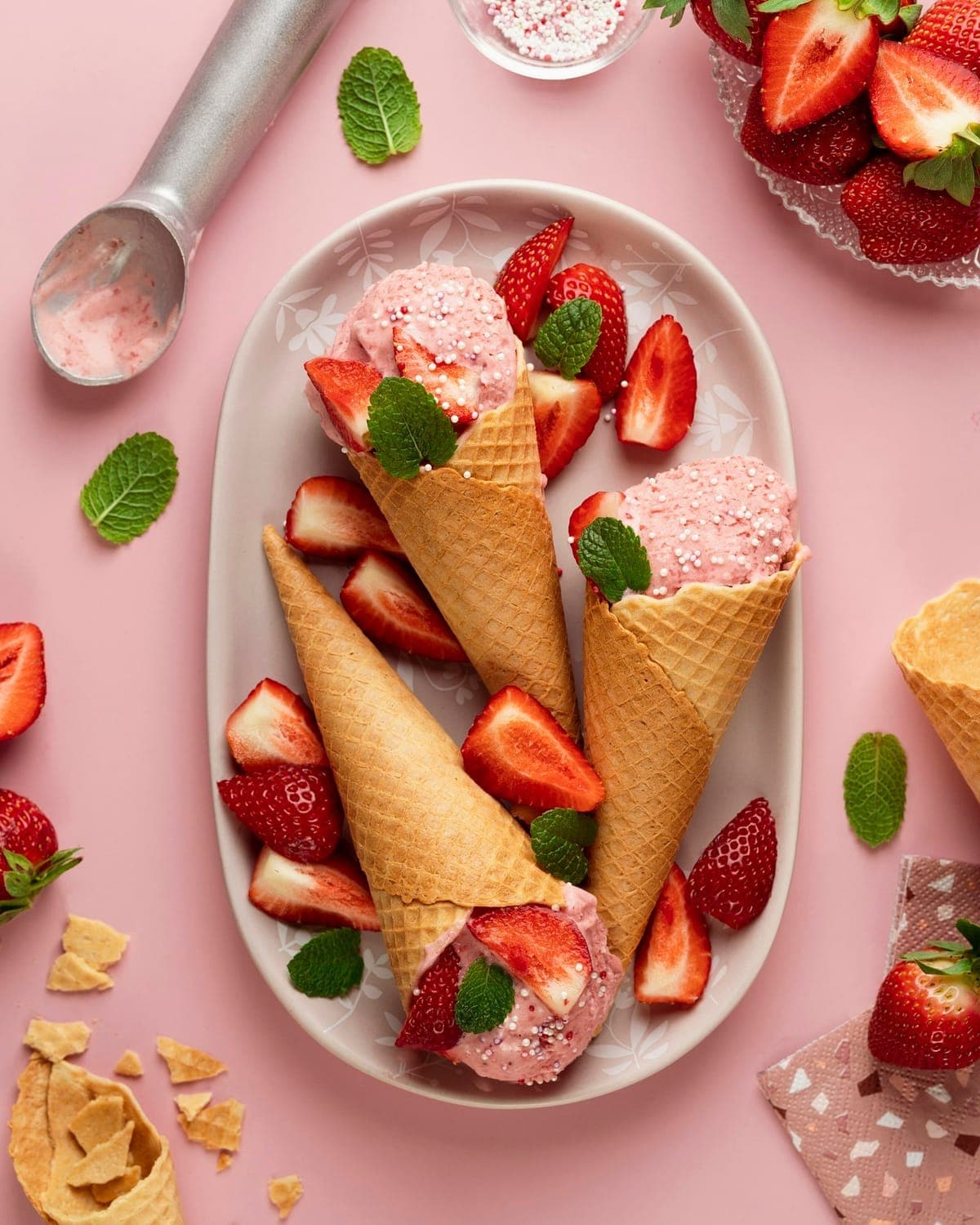 Waffle cones with strawberry custard and fresh strawberries on a pink platter