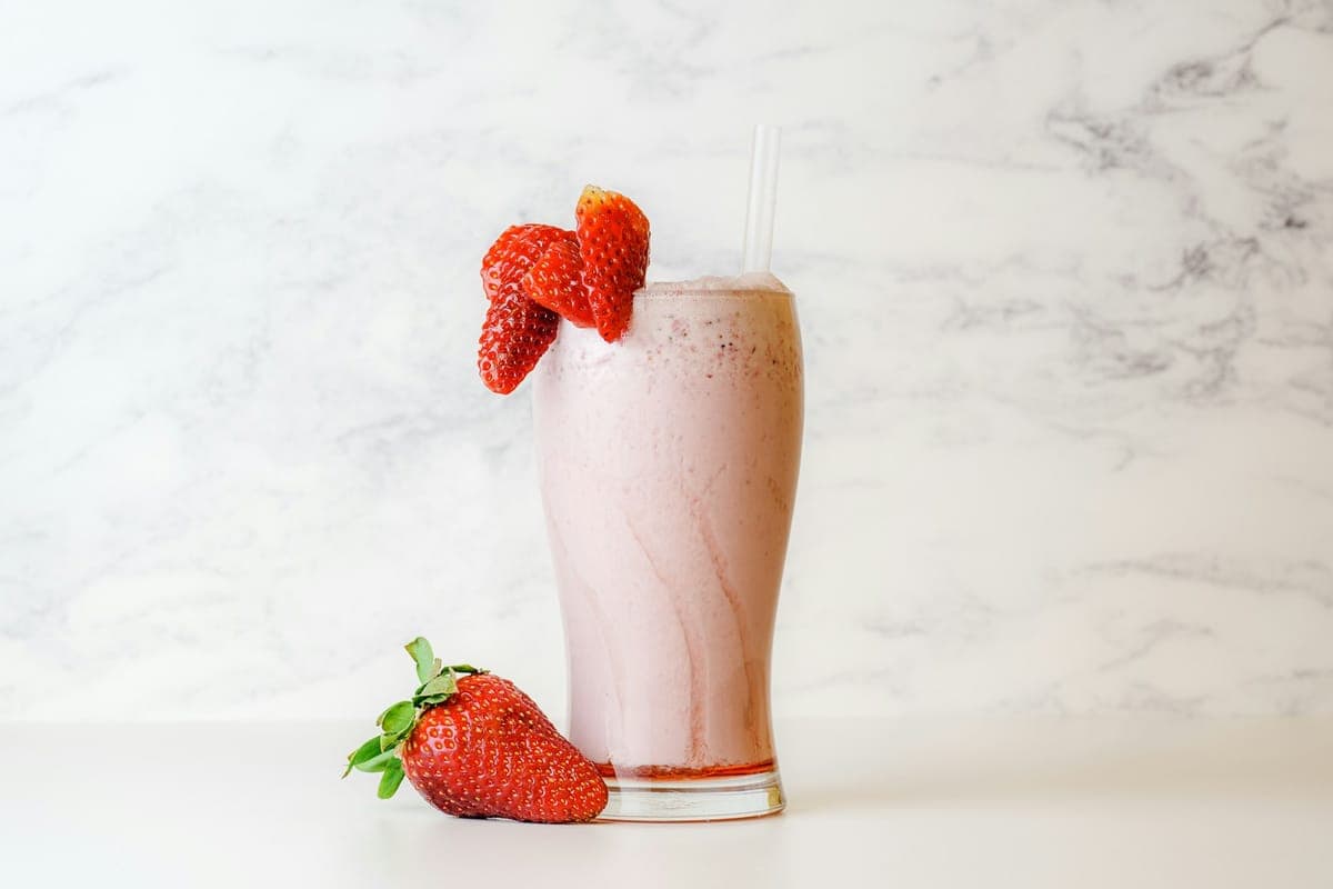Strawberry Porch Shake with fresh strawberries on the rim of a tall glass